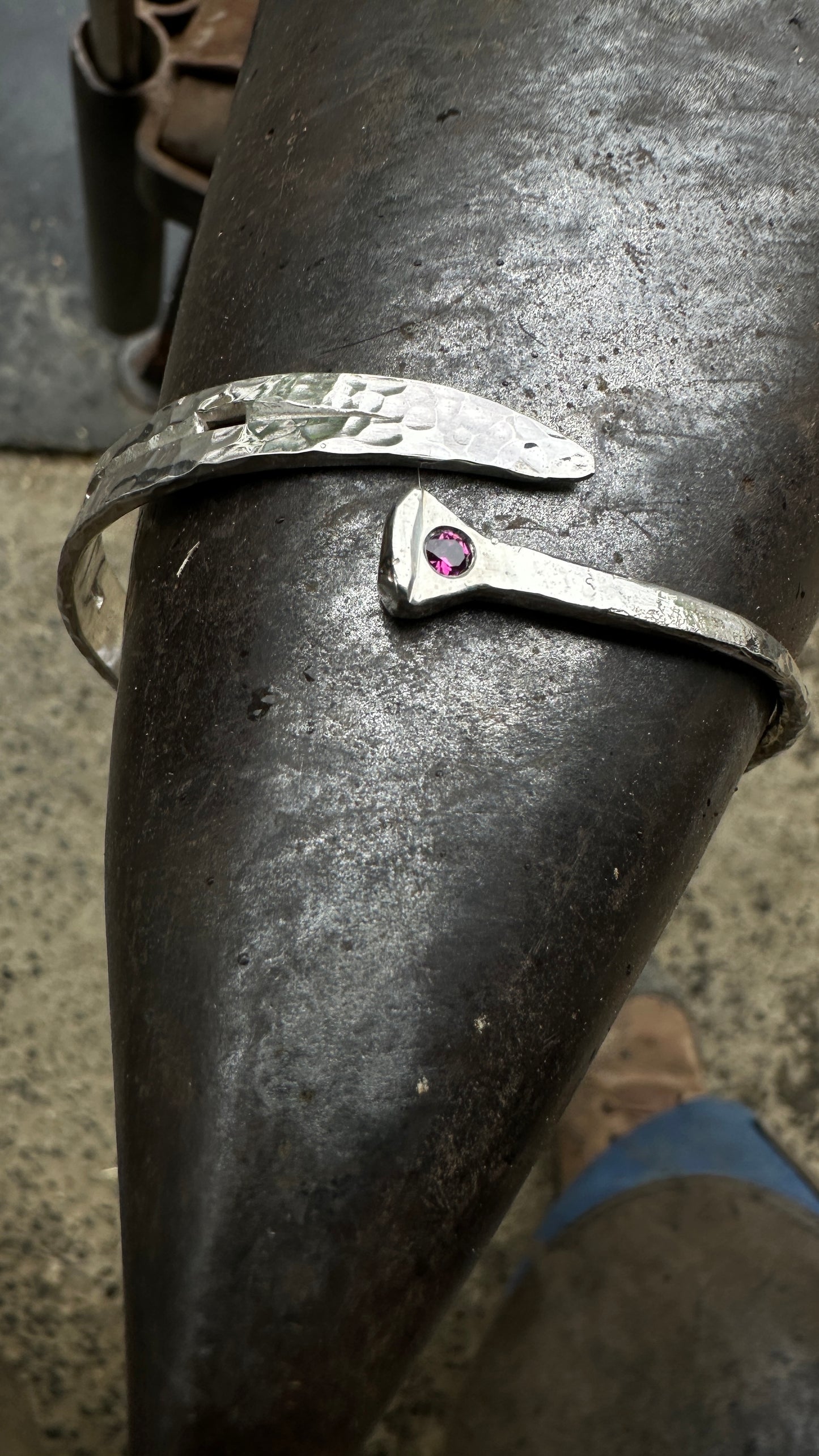 Silver bracelet with a red gemstone on a dark surface