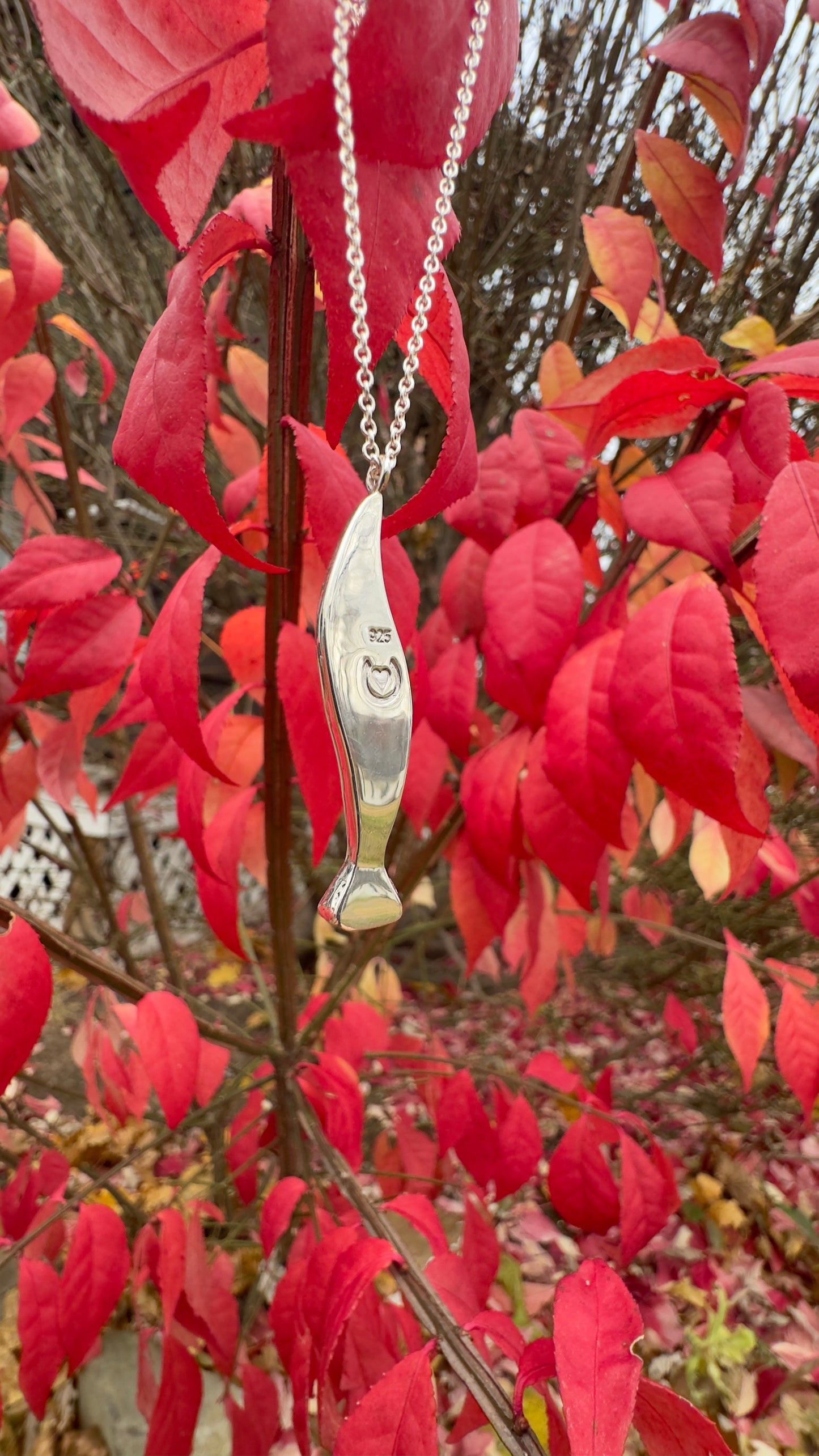 Necklace with a pendant hanging from red leaves