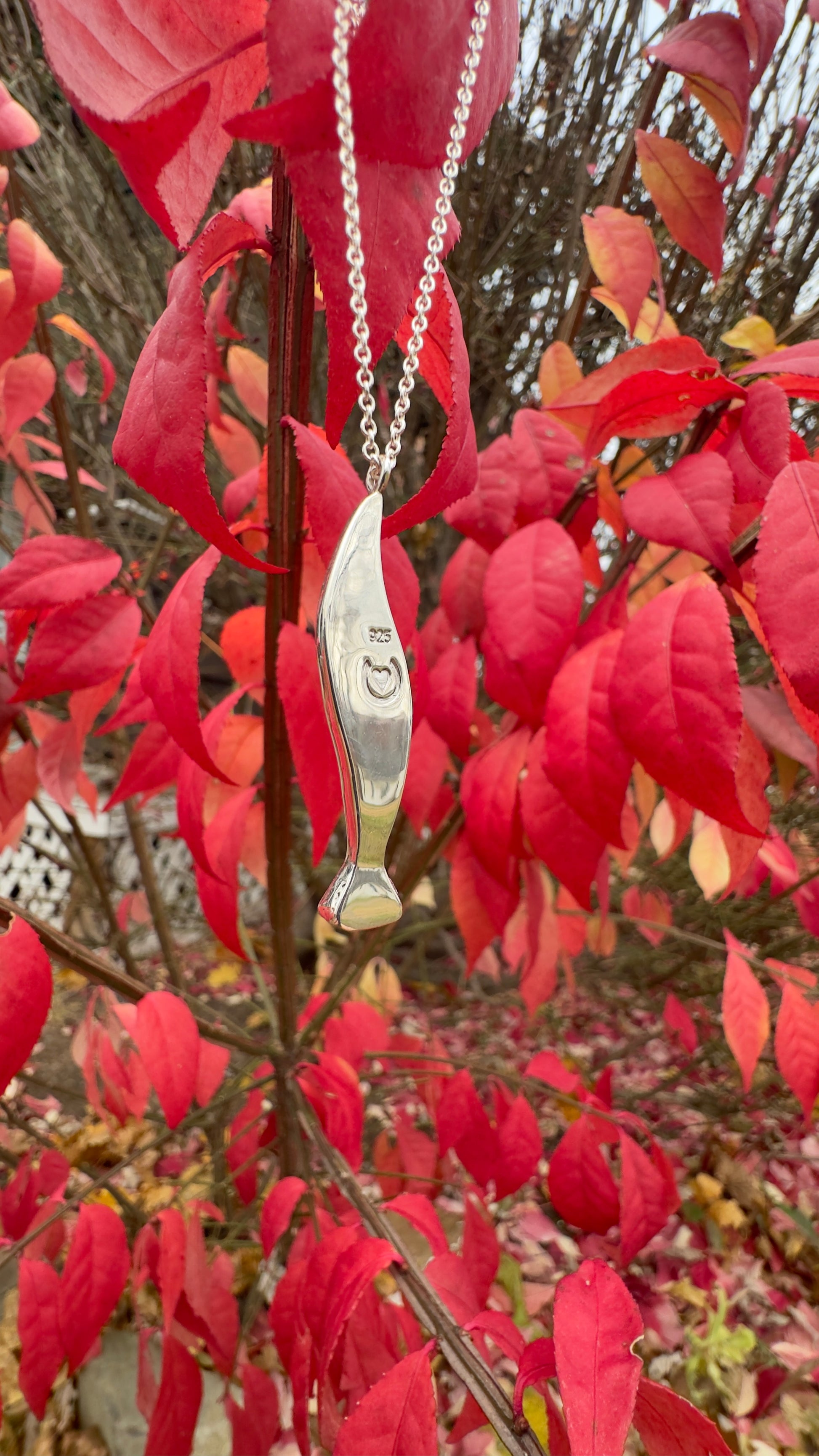 Necklace with a pendant hanging from red leaves