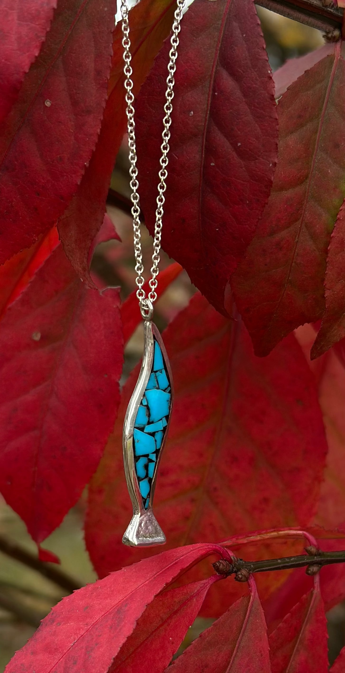 Silver and turquoise pendant against red leaves
