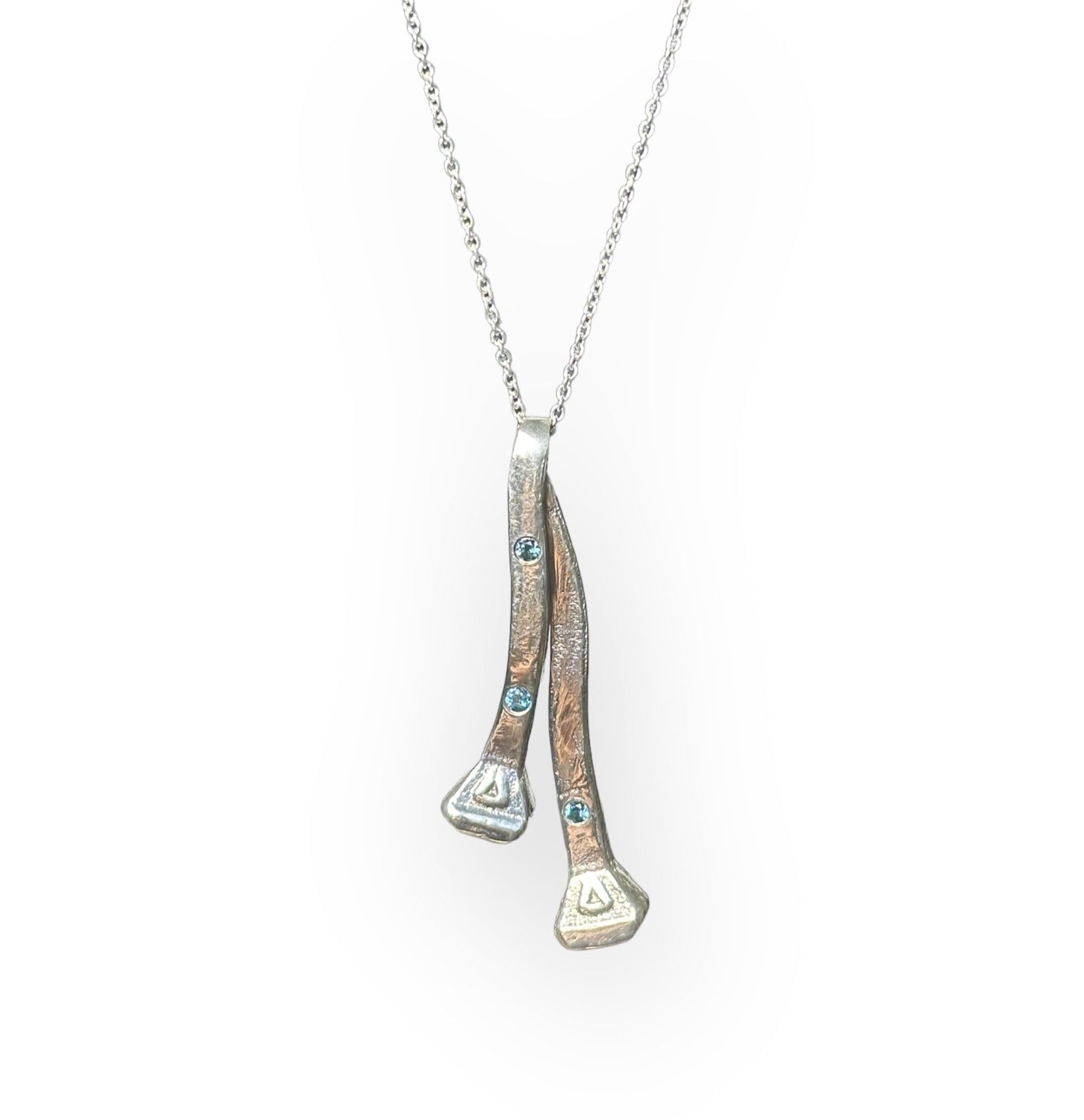 Two silver horseshoe nails on a chain with three flush set London blue topaz