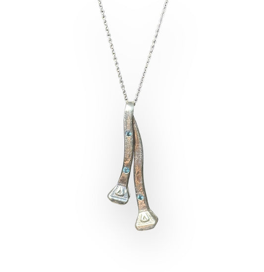 Two silver horseshoe nails on a chain with three flush set London blue topaz